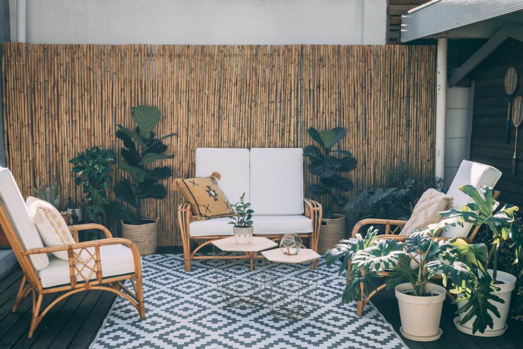 A large outdoor entertaining area with a rug and a bamboo fence